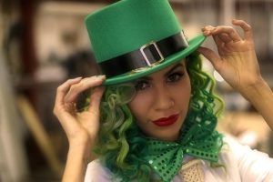Kobieta w zielonym kapeluszu z zielonymi włosami i zieloną muszką, która nawiązuje do irlandzkich tradycji.